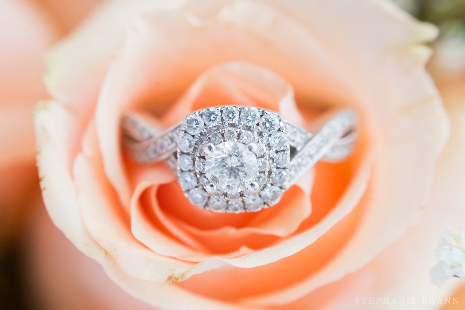halo wedding ring sitting in coral flowers