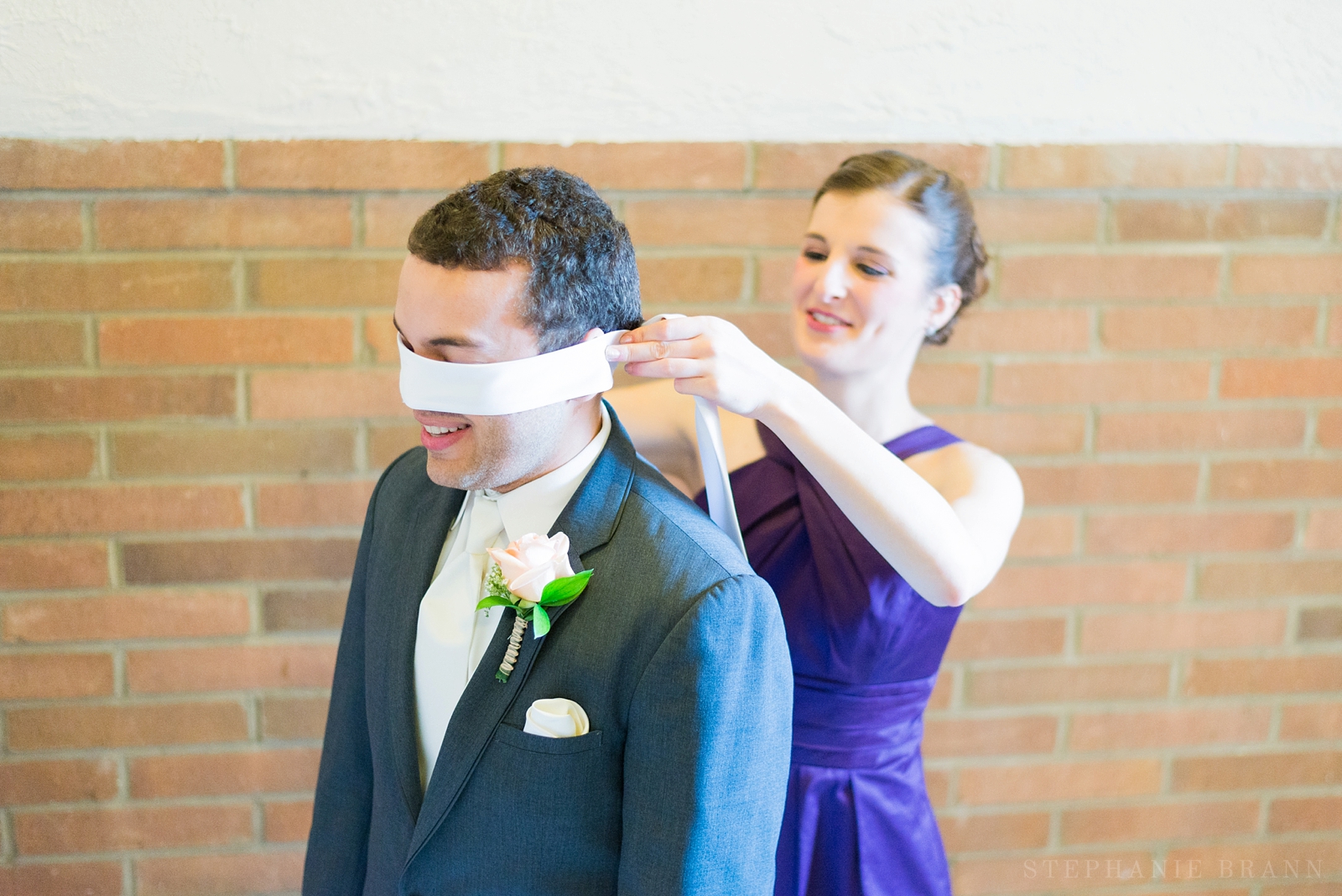 girl blindfolding a groom for a prayer