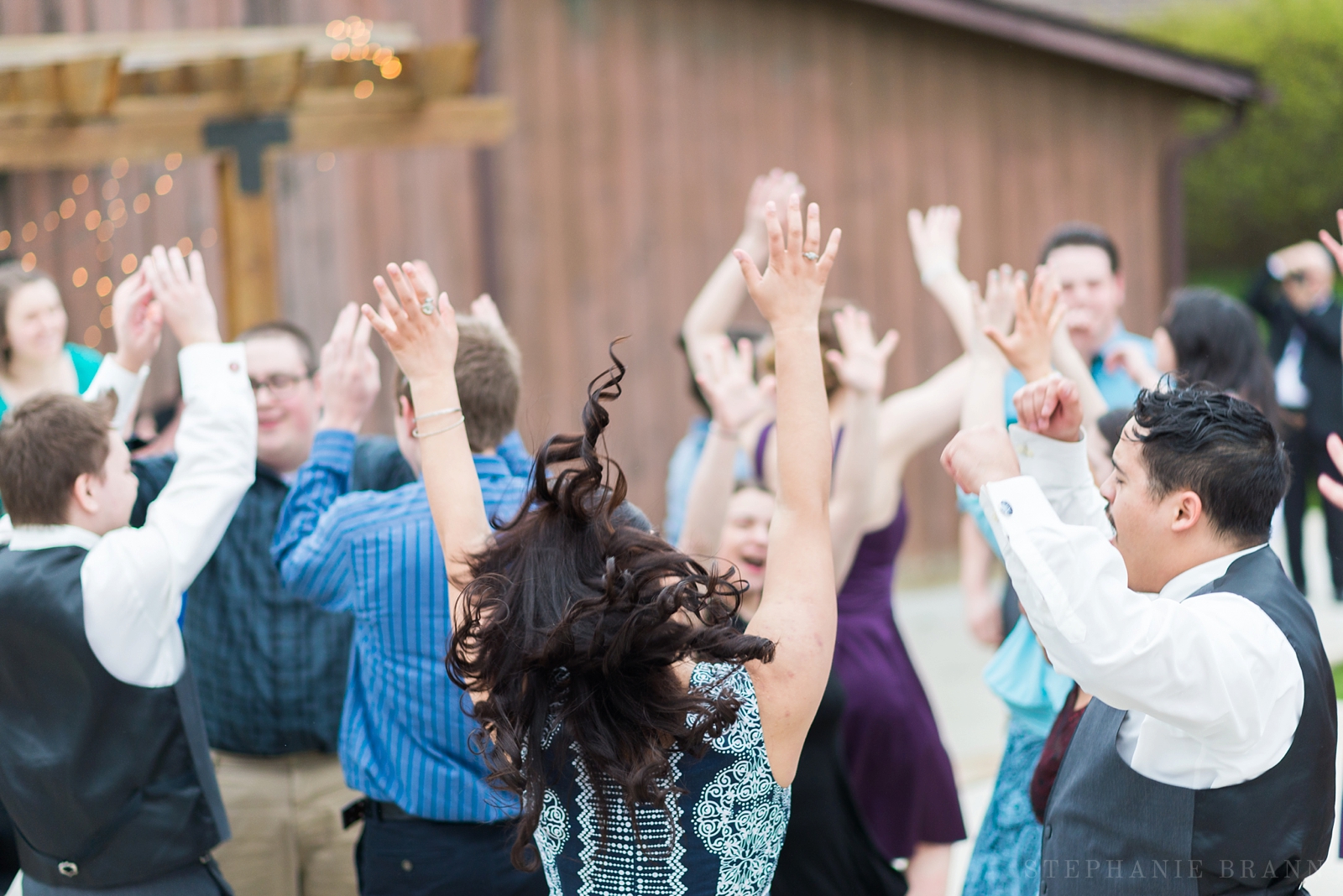 wedding guests dancing outside of a barn