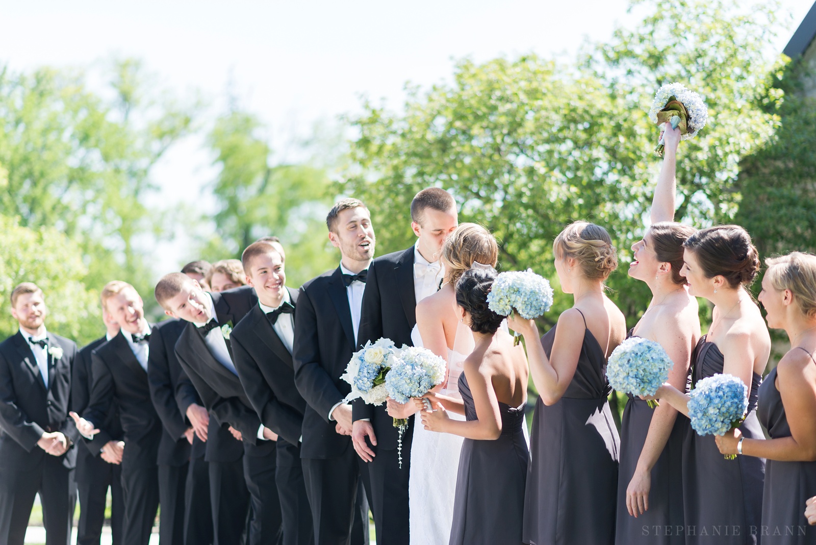 fun-bridal-party-group-photo-with-couple-kissing