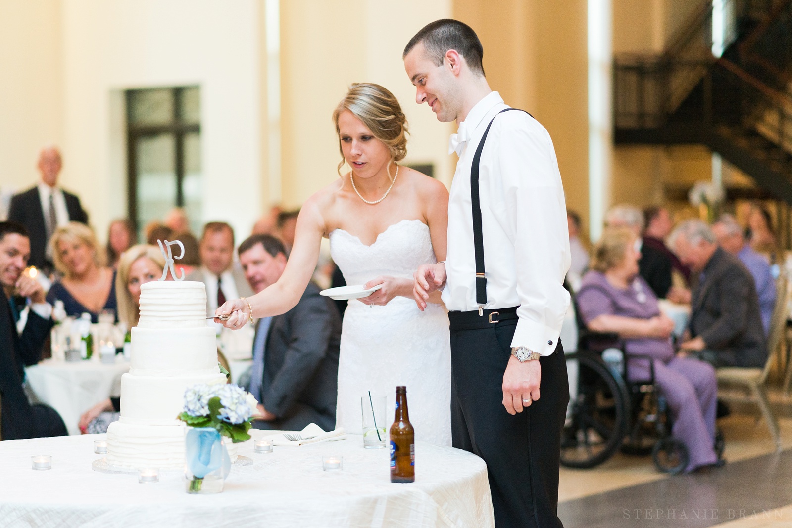 couple-cutting-their-wedding-cake-surrounded-by-their-guests