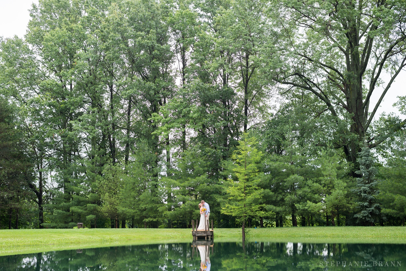 bride-and-groom-kissing-by-a-pond-with-huge-trees-over-them