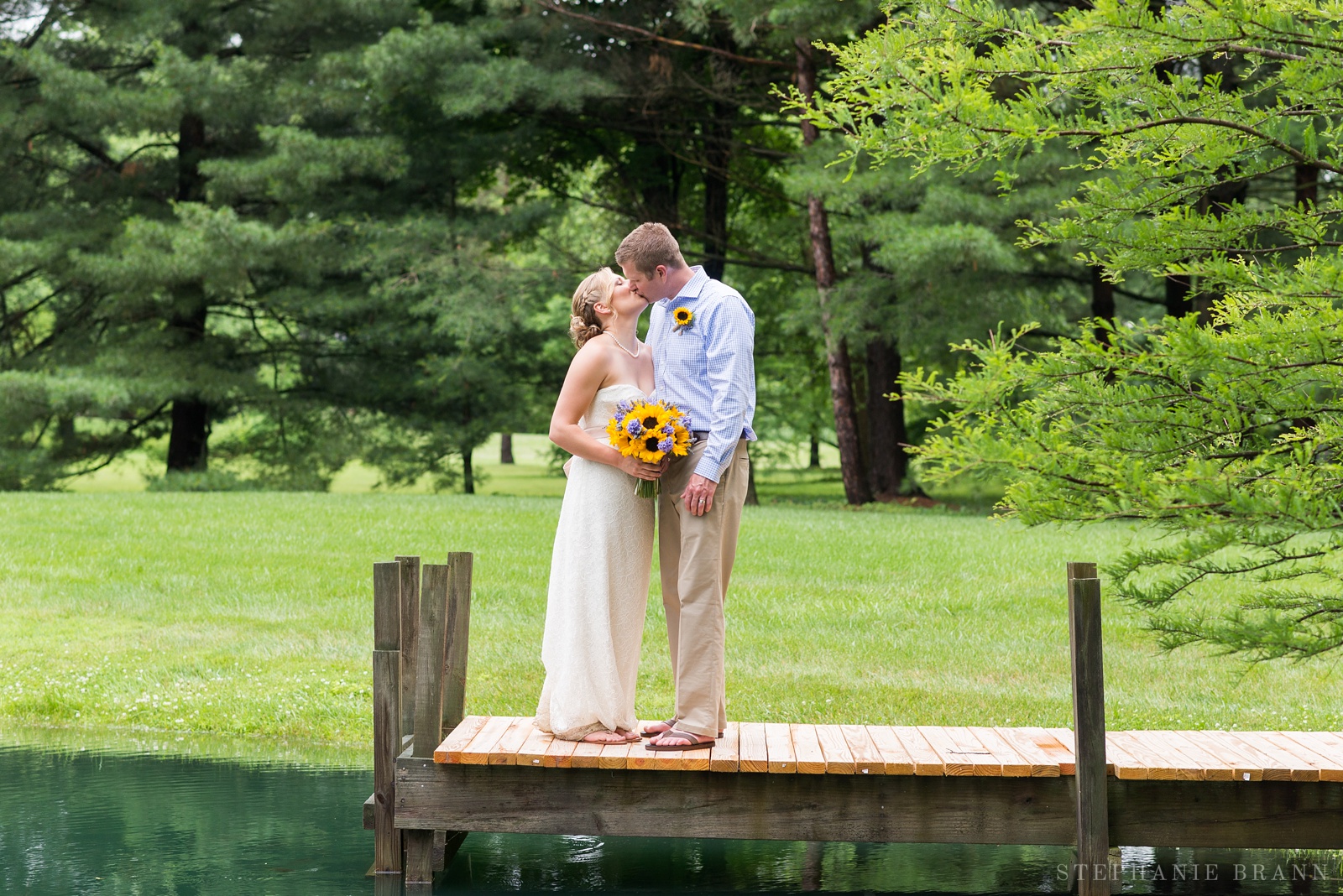 wedding-couple-kissing-on-a-wooden-dock-by-a-pond