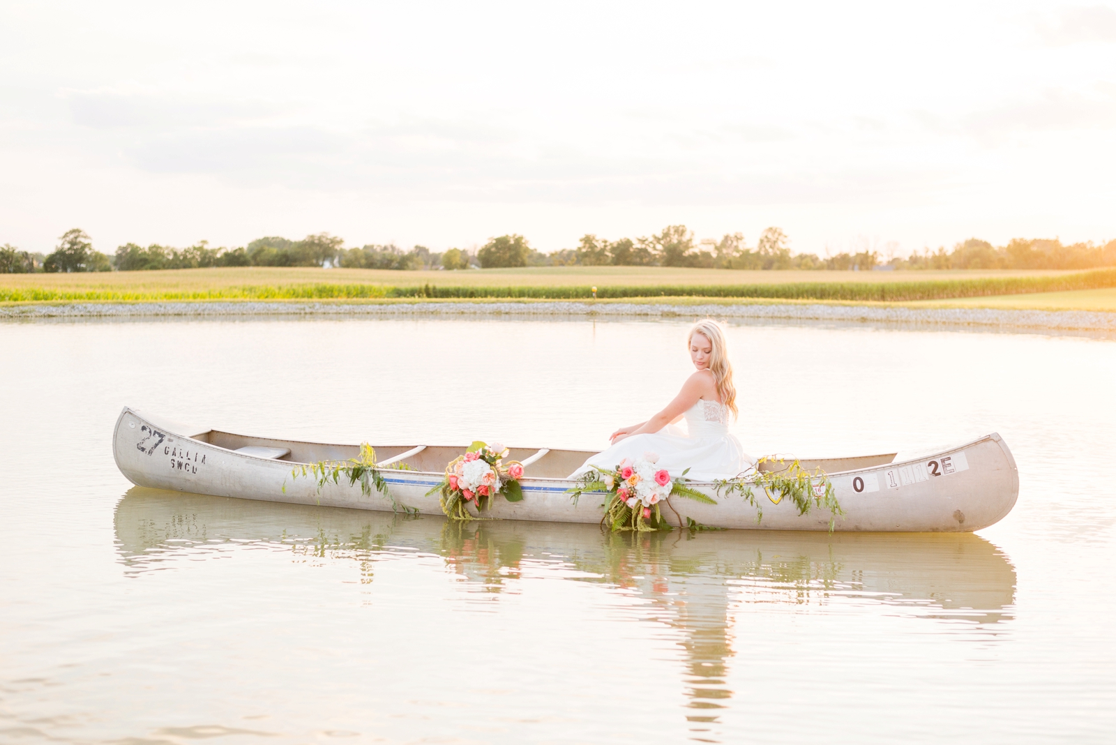 girl-in-her-wedding-dress-sitting-in-a-canoe-on-a-lake-at-sunset