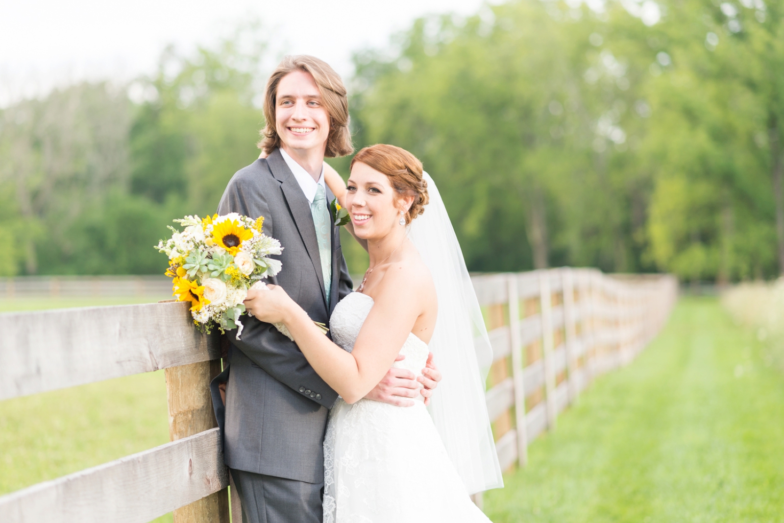 couple-posing-for-portraits-with-a-bouquet-made-of-yellow-sunflowers
