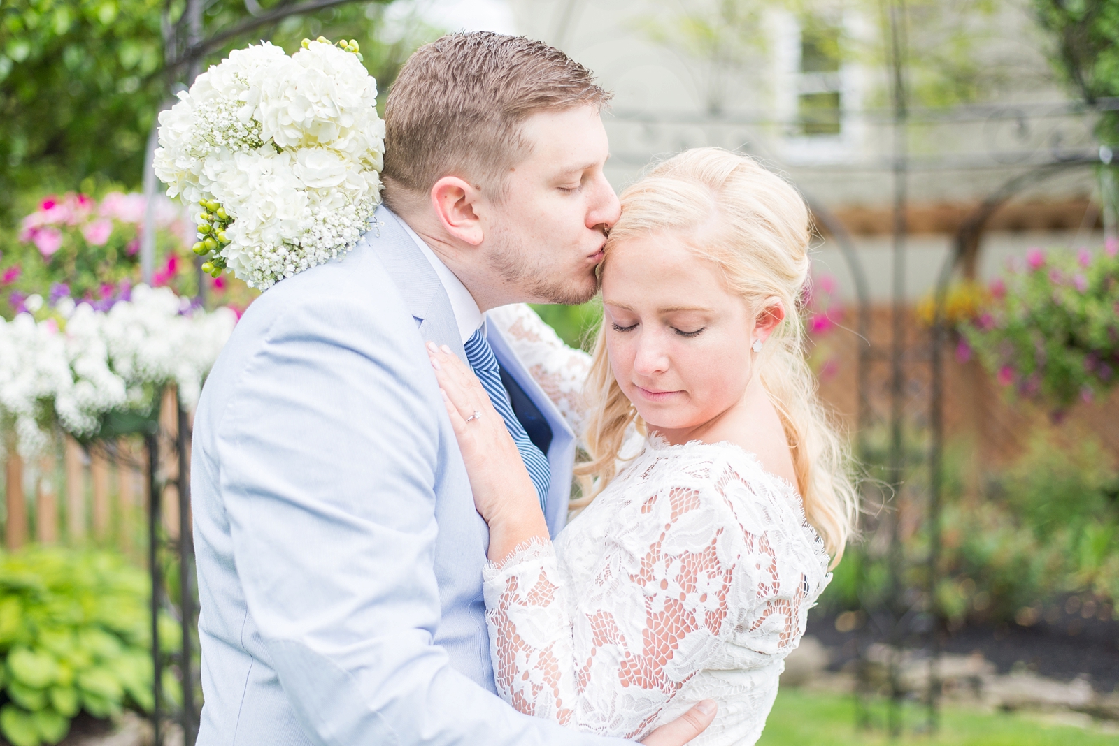 bride-holding-a-bouquet-while-her-groom-is-kissing-her-forehead