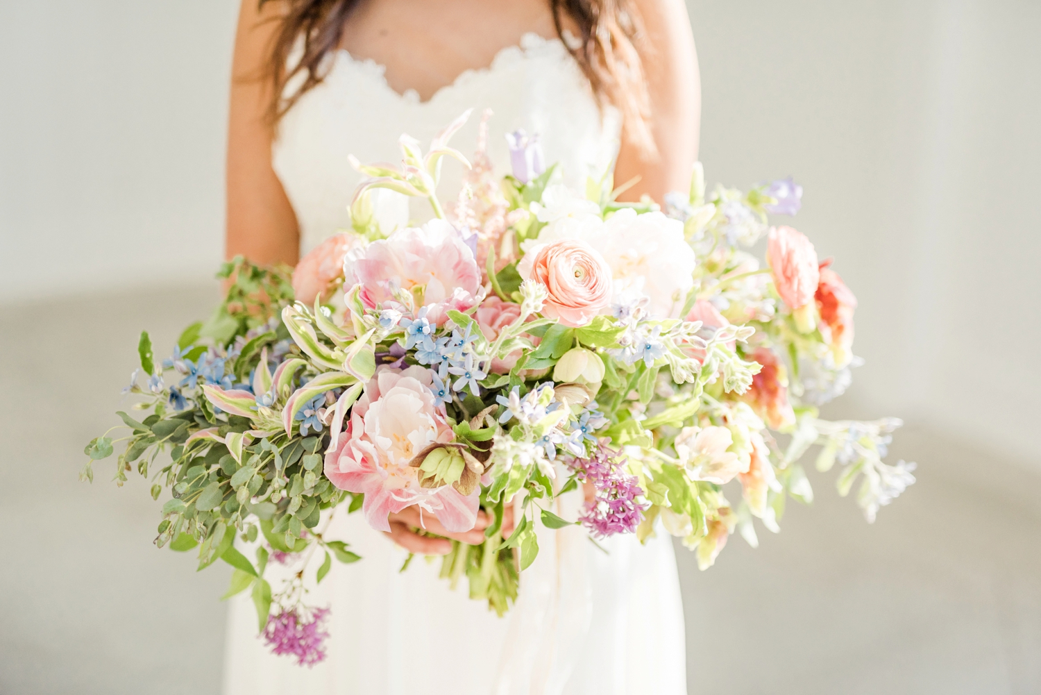 bride-holding-a-gorgeous-floral-bouquet-with-greenery-and-spring-florals
