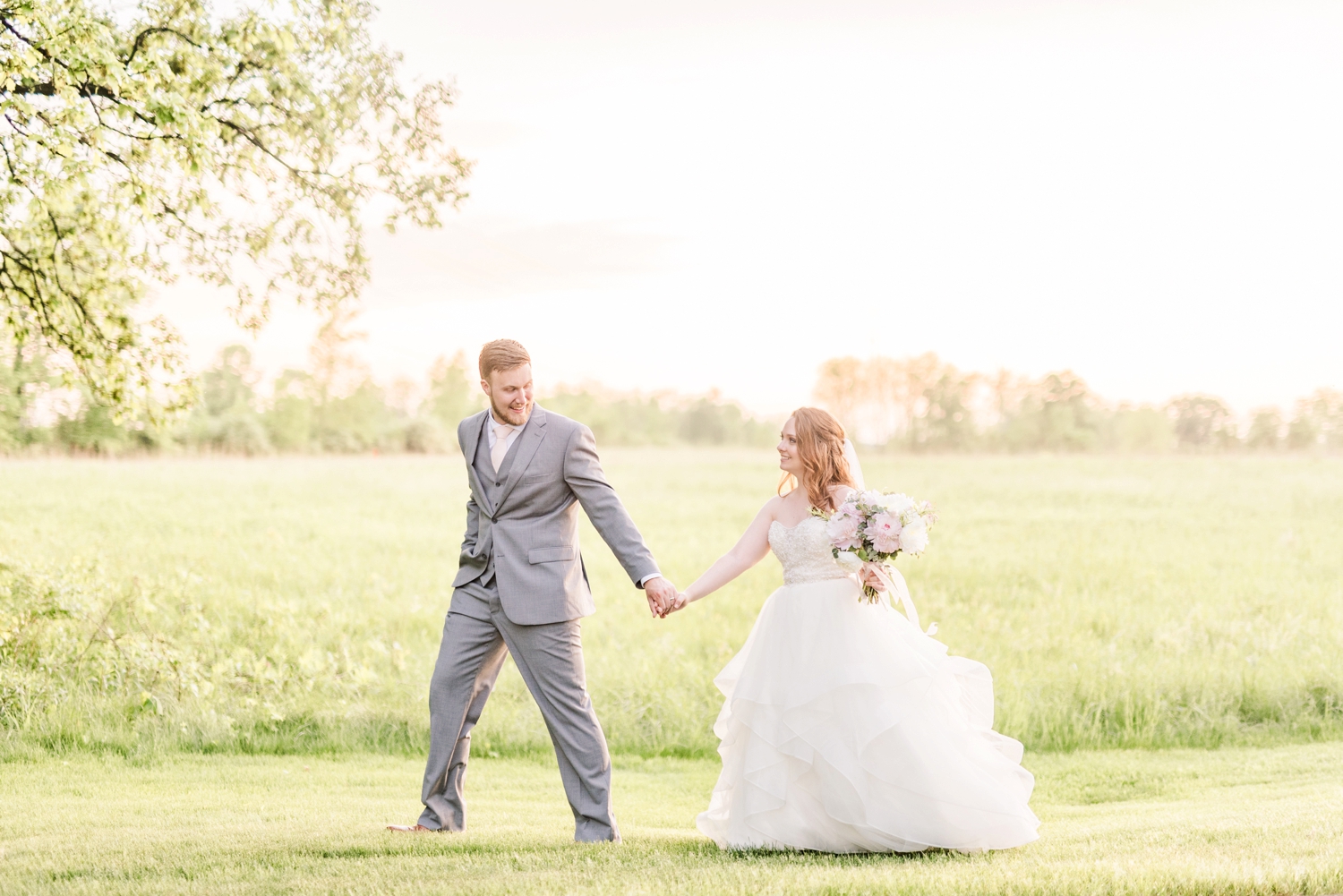 bride-and-groom-walking-through-a-field-at-sunset