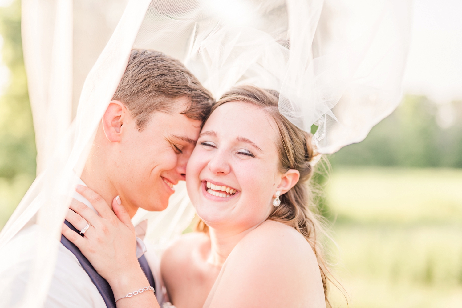 couple-laughing-with-joy-on-their-wedding-day-with-the-veil-flowing