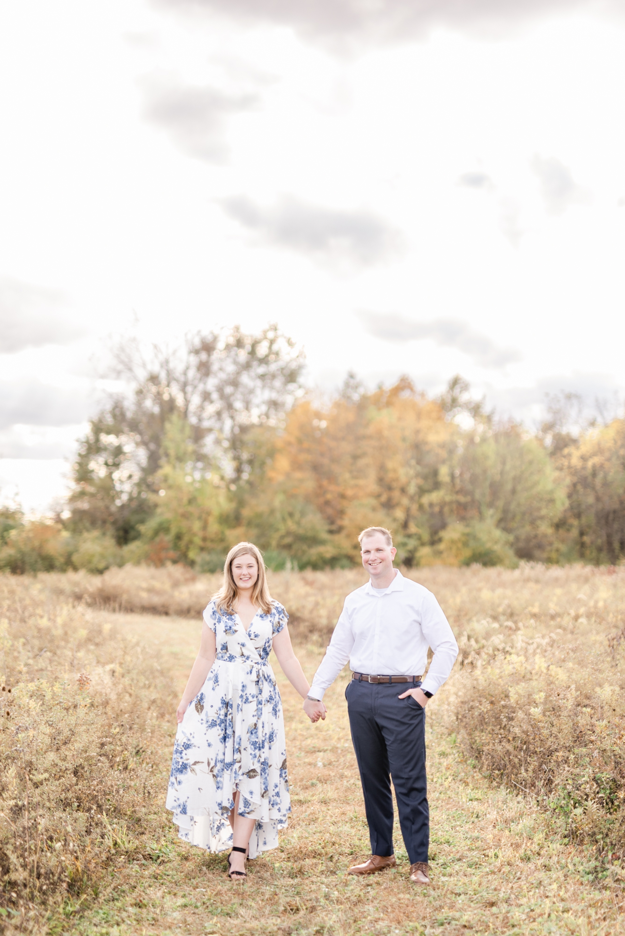 portrait-of-an-engaged-couple-standing-and-holding-hands-in-a-field