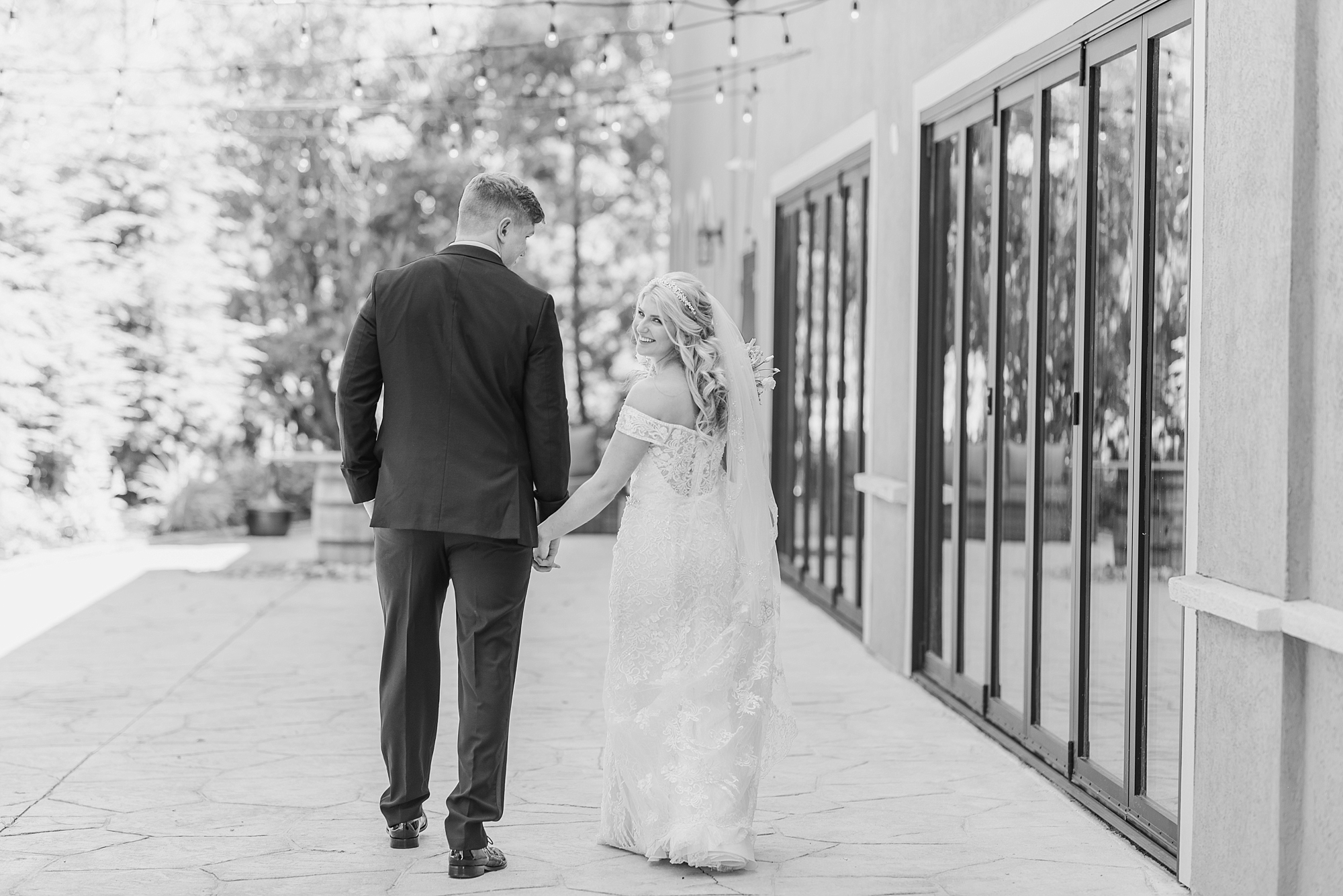 bride and groom hold hands walking away from photographer during first look at Brookshire