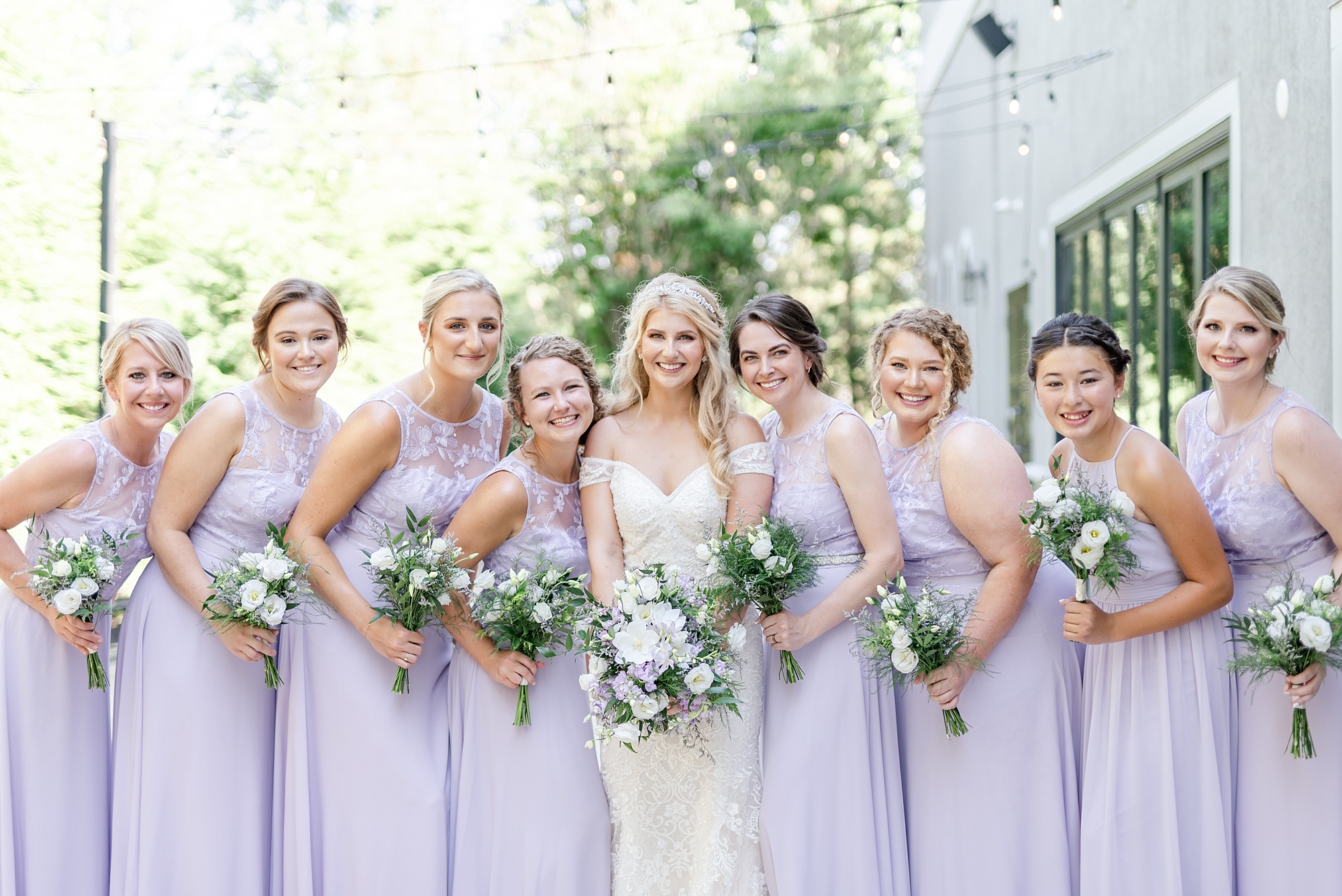 bridesmaids in purple gowns pose with bride