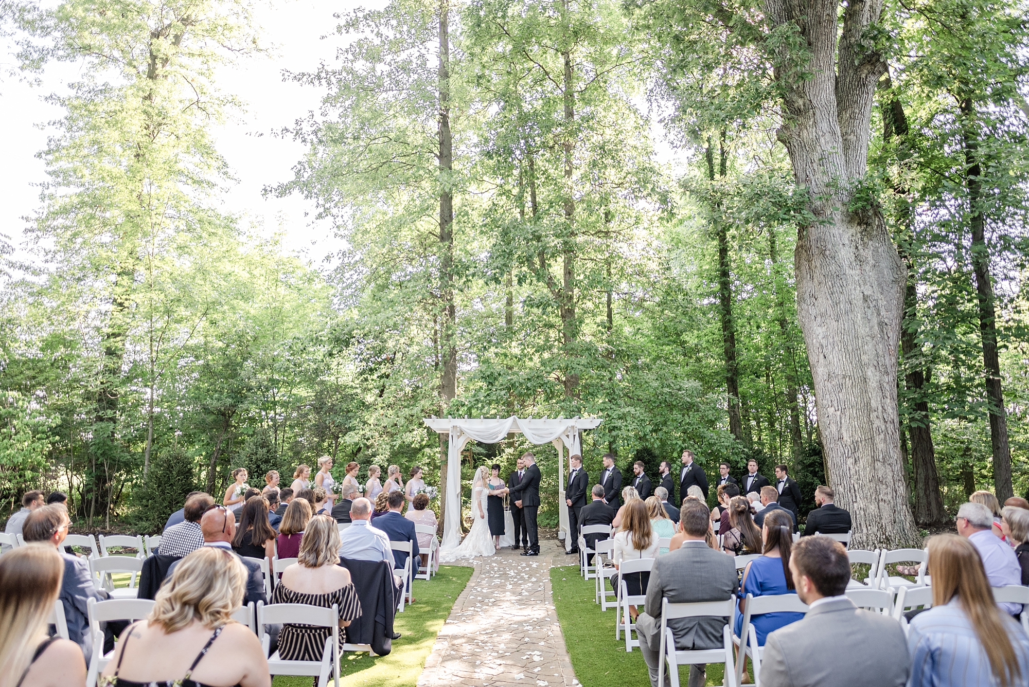 outdoor wedding ceremony with white arbor photographed by Stephanie Kase Photography