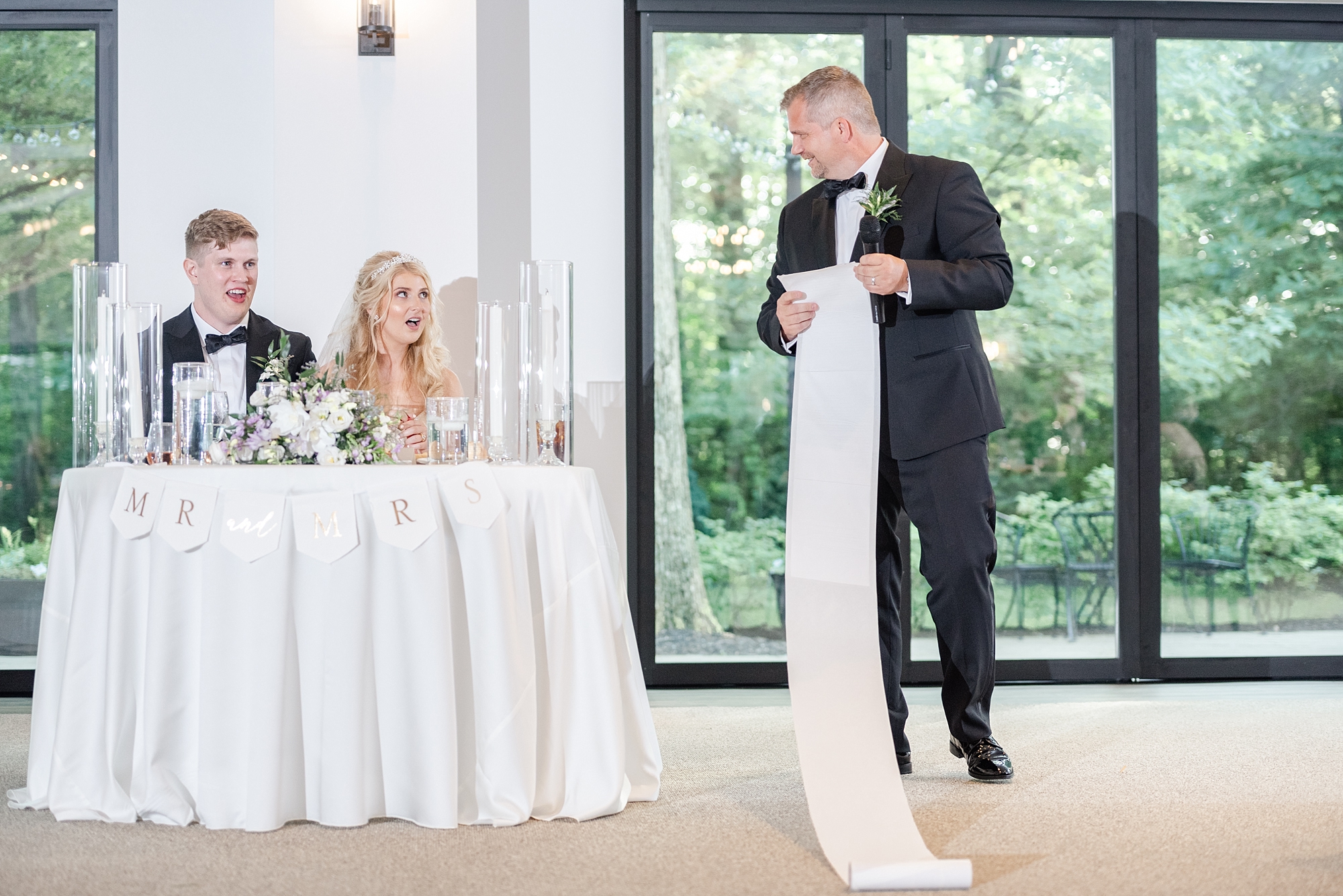 father of bride reads toast off of paper touching the floor as a joke for bride and groom