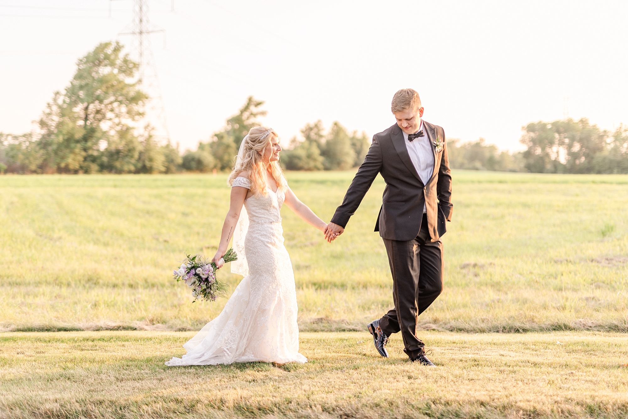 sunset wedding portraits of bride and groom holding hands while walking at Brookshire
