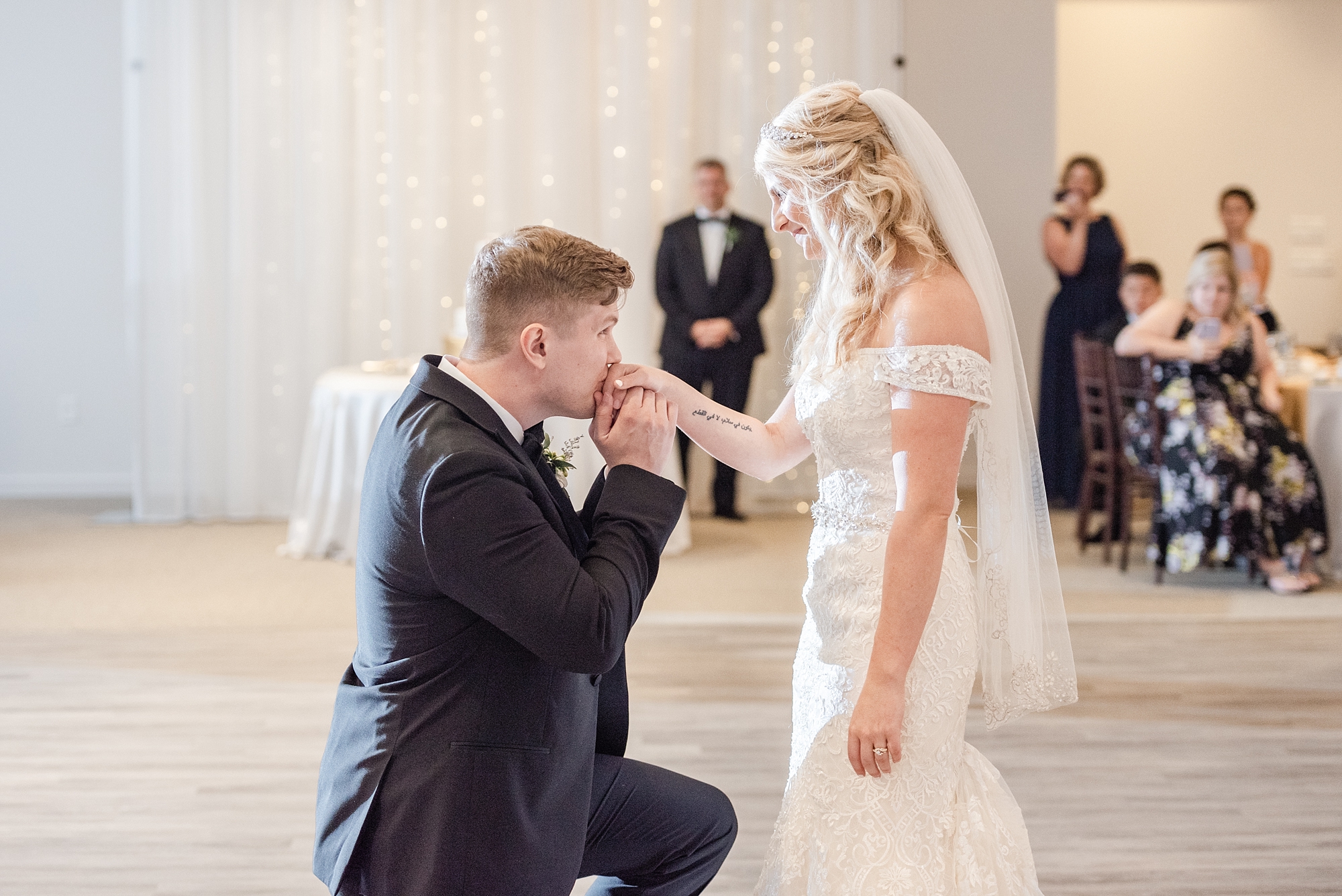 groom kisses bride's hand during wedding dance