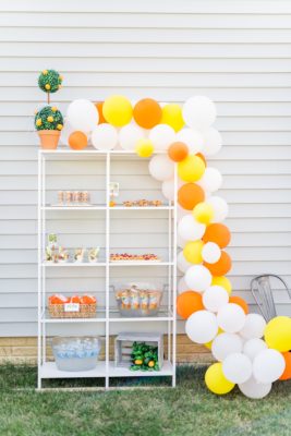 balloon garland with orange, yellow, and white balloons for baby shower in backyard