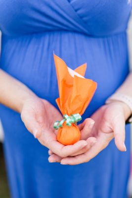 mom in blue dress holds party favor for backyard baby shower