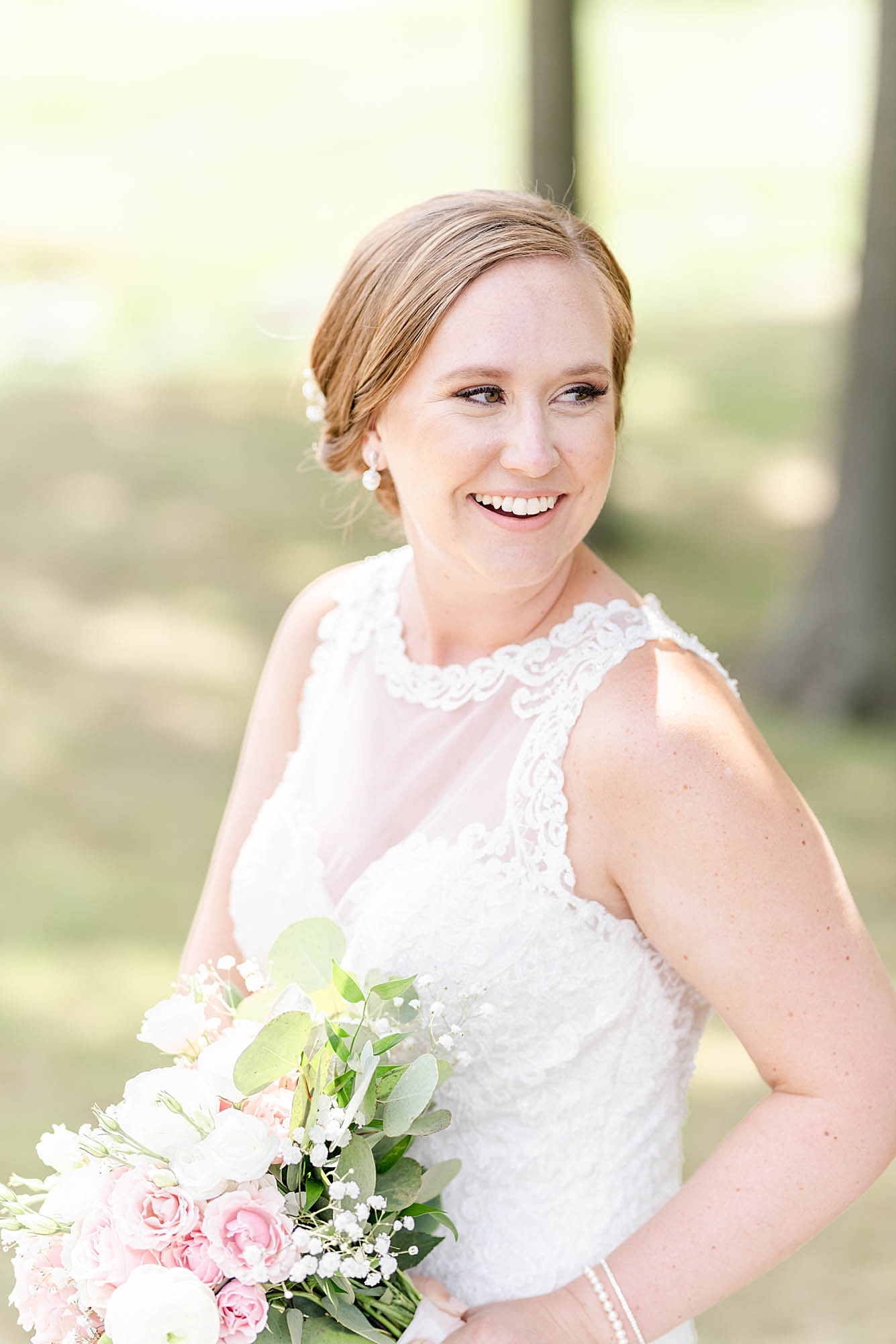 bride laughs while looking over shoulder holding bouquet with pink flowers