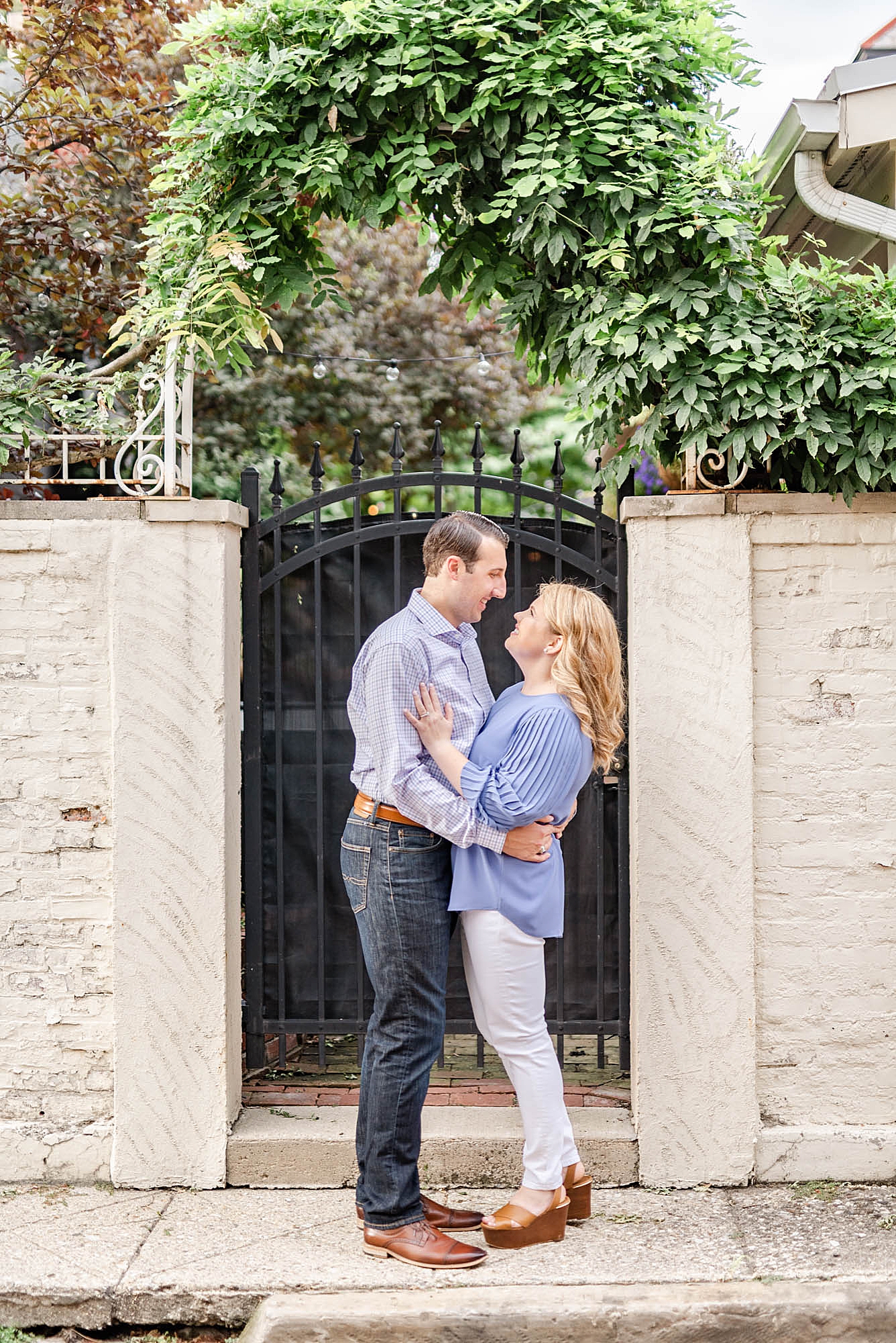 bride and groom pose by wrought iron gate in Ohio