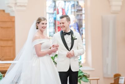 bride and groom smile at guests during wedding ceremony