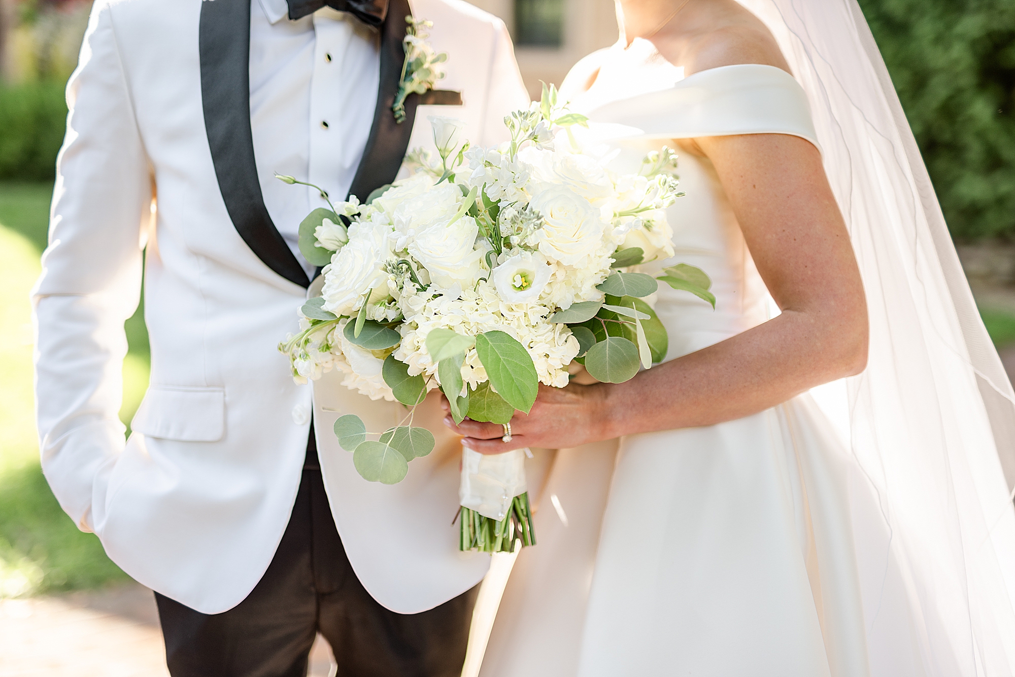 bride holds bouquet while posing with groom