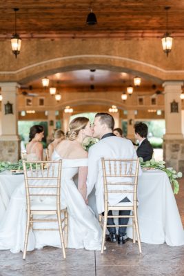newlyweds kiss at sweetheart table at Ohio vineyard