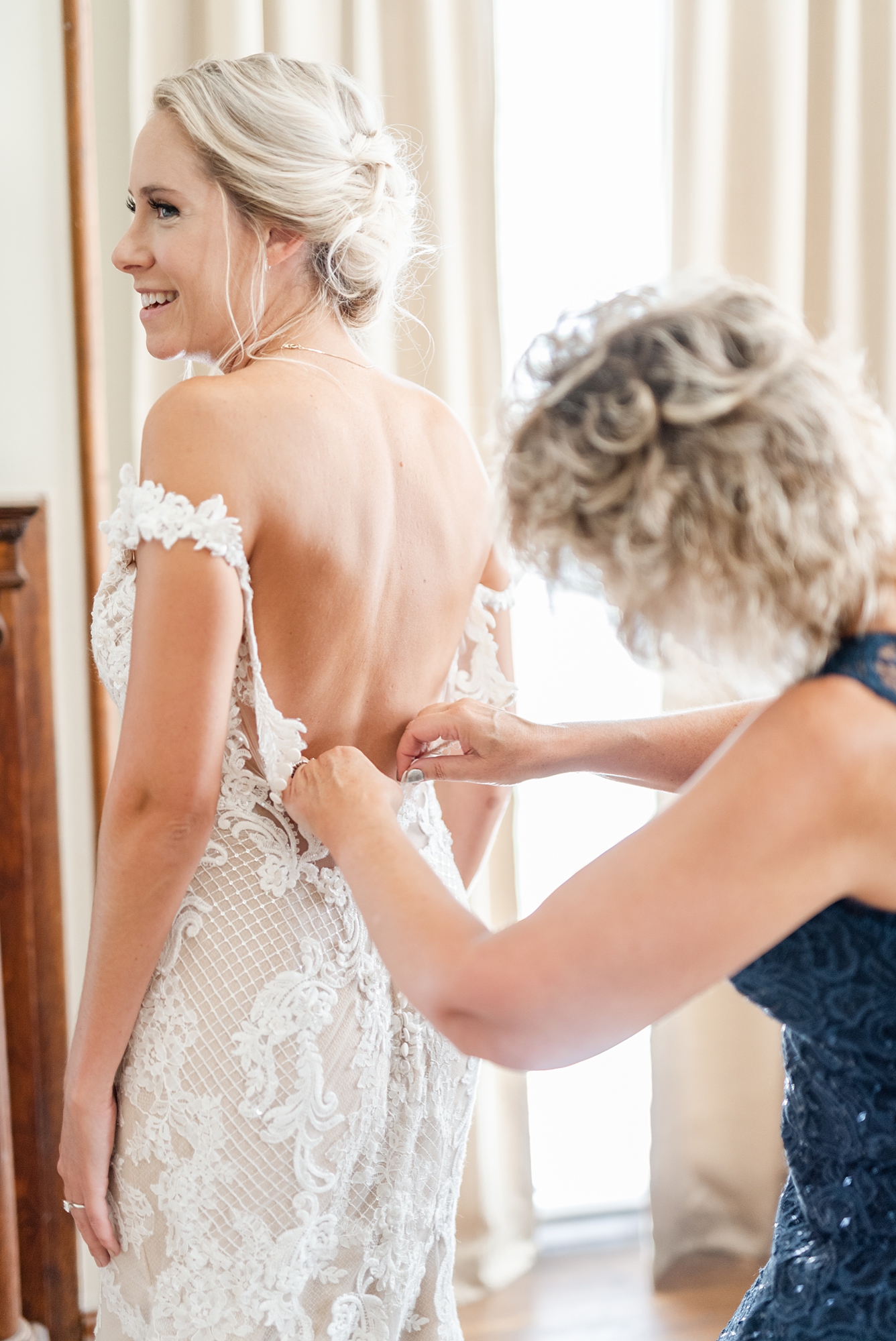 bride's mother helps with gown during wedding morning prep