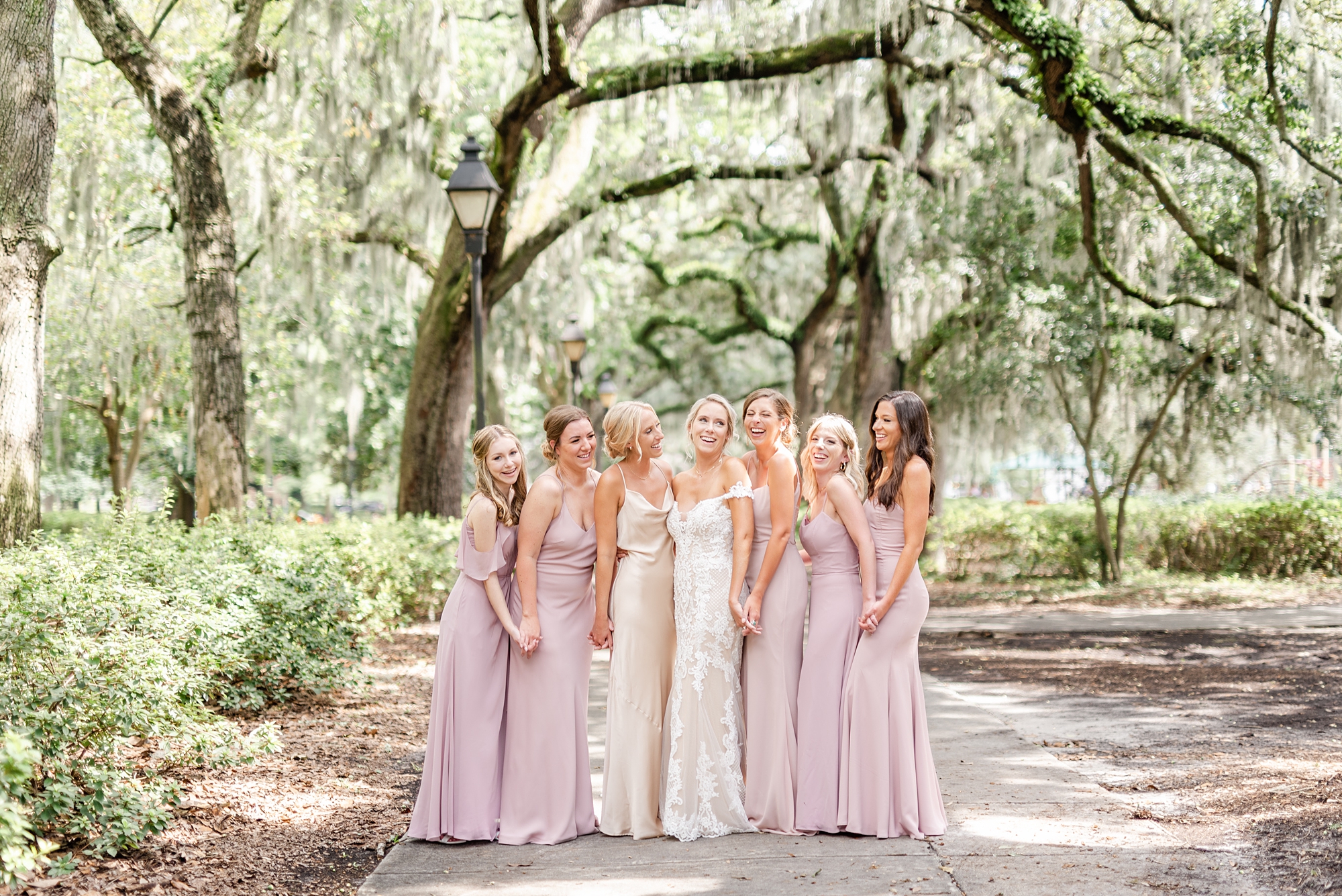 bride and bridesmaids in pink dresses pose under Spanish moss in Savannah GA