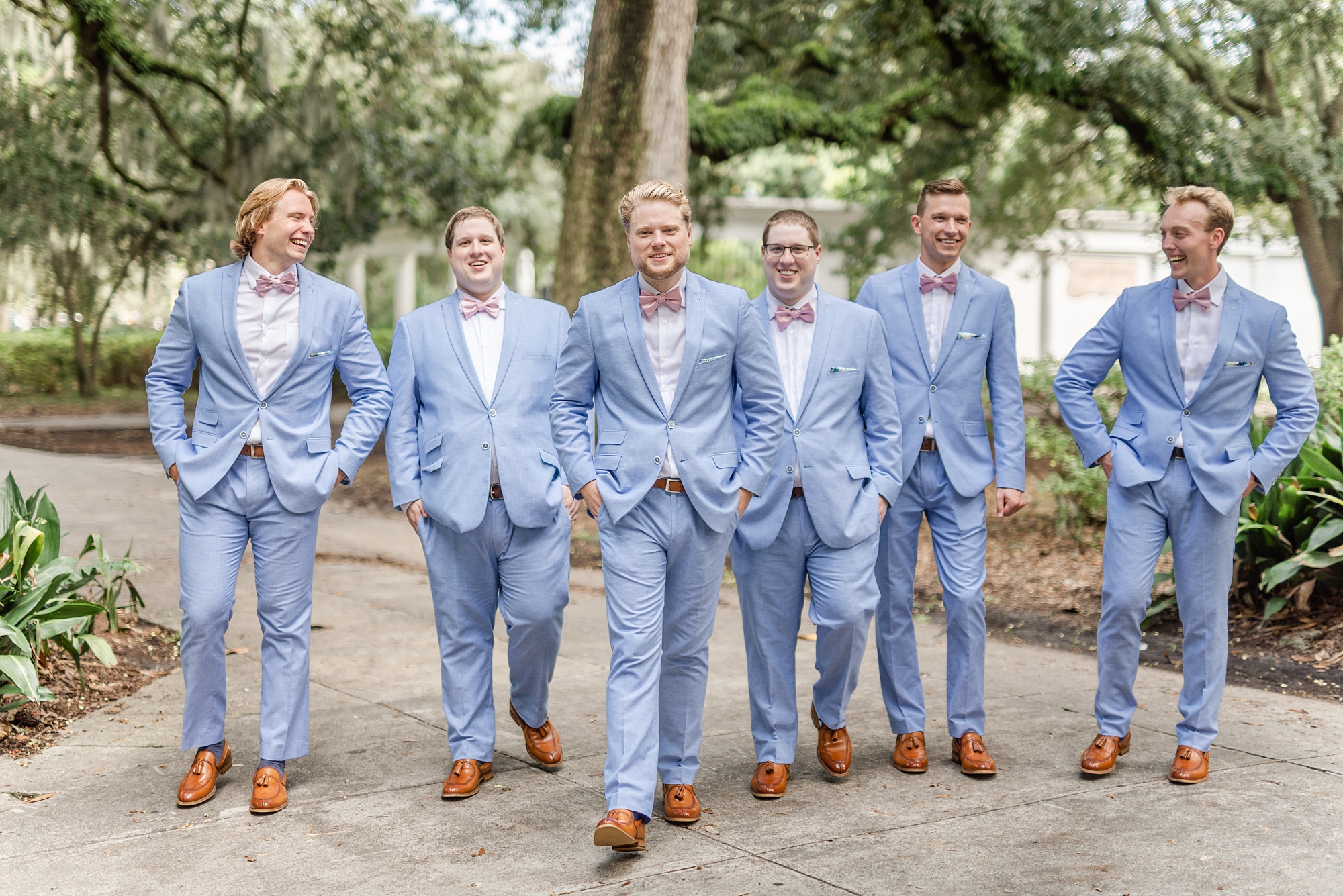 groom walks with groomsmen in light blue suits for southern wedding