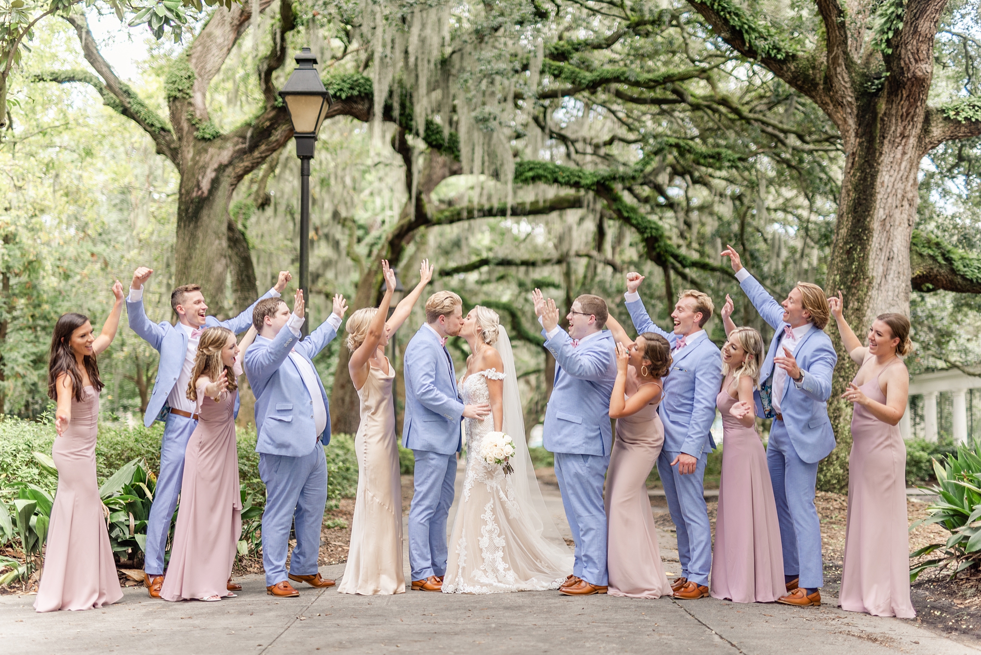 bridal party in pastel blue and pink cheer during wedding party portraits