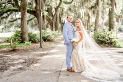 newlyweds pose under Spanish moss with bride's veil trailing in Savannah GA