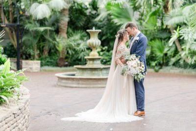 bride and groom pose by fountain in Franklin Park Conservatory