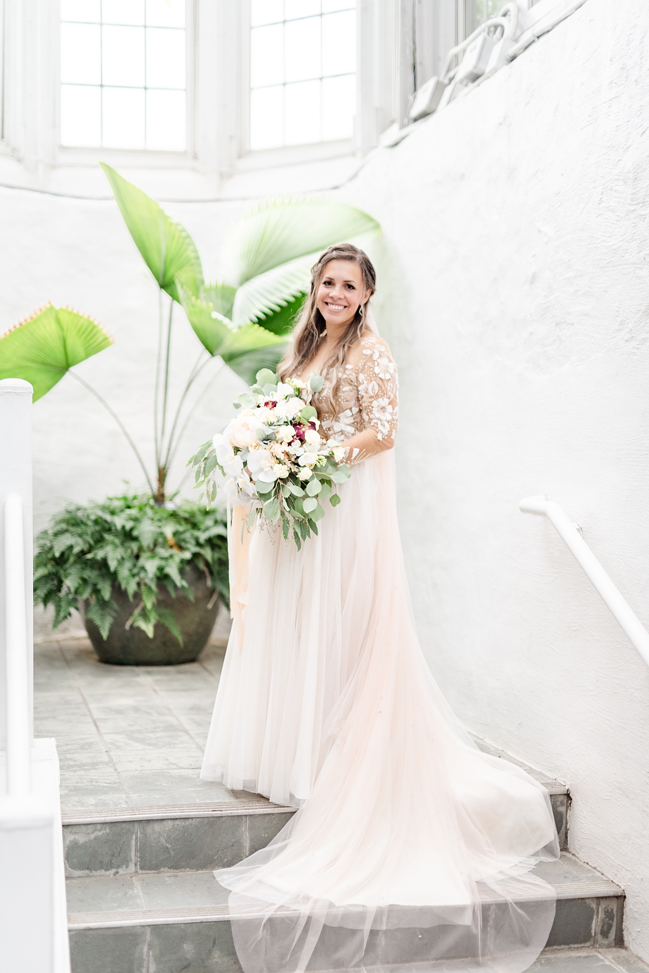 bride stands on white staircase in Franklin Park Conservatory