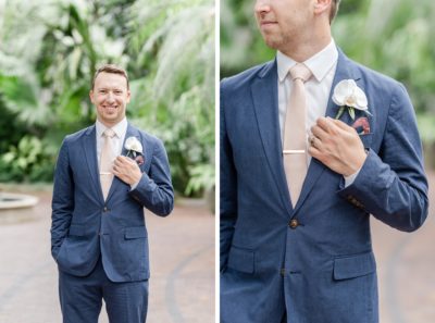 groom in navy suit with pink tie poses in Franklin Park Conservatory
