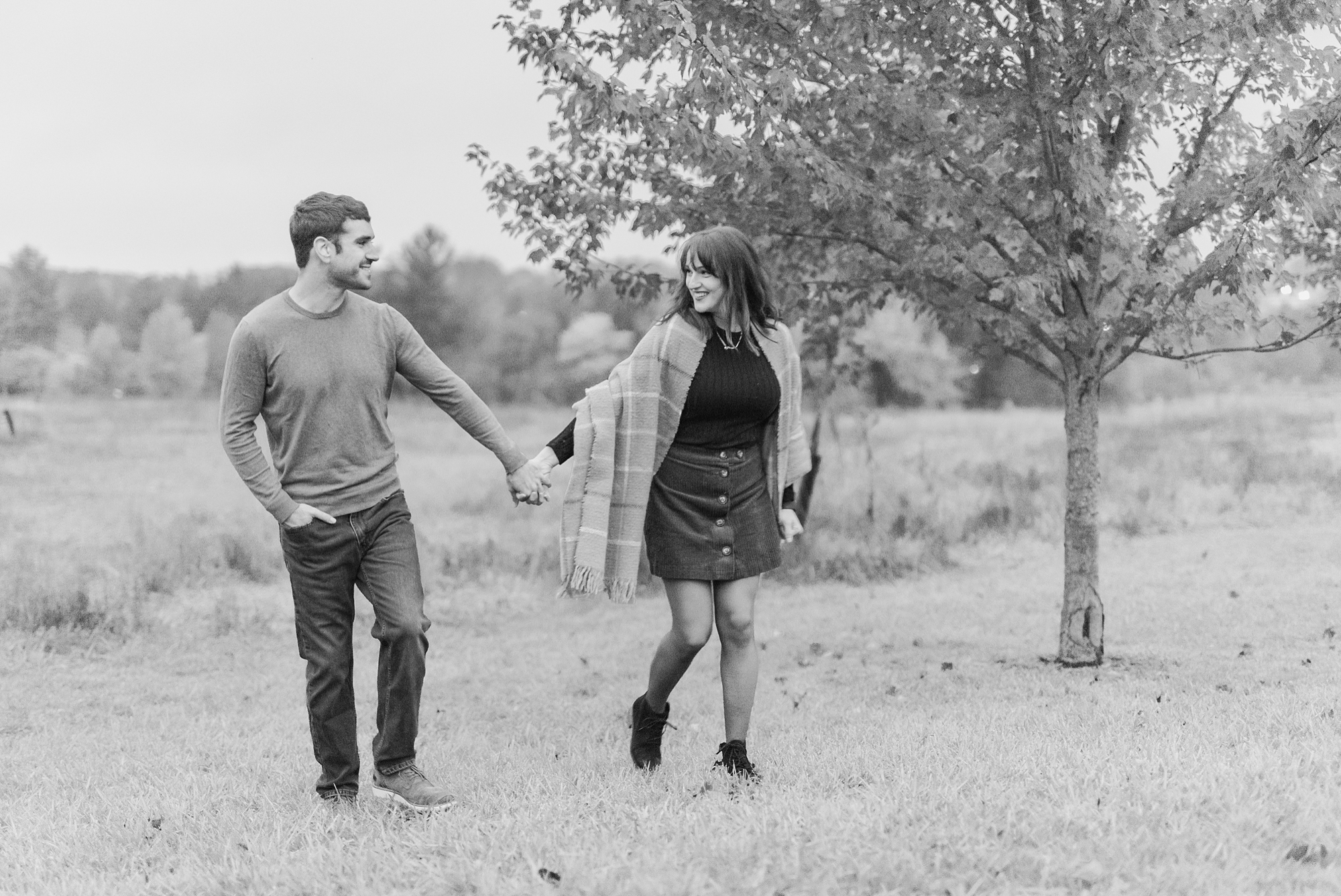 couple holds hands walking along lake