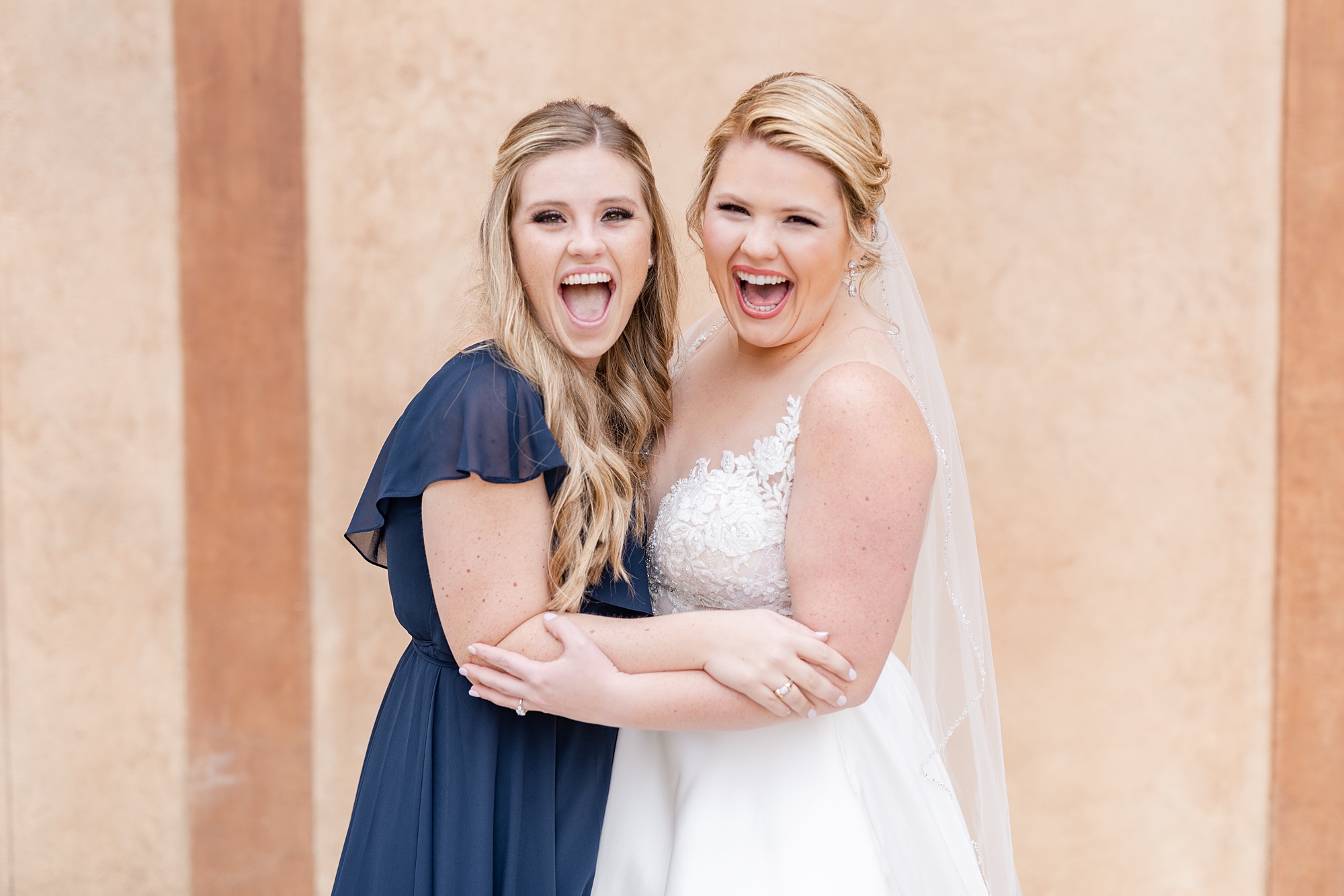 bride and sister cheer during wedding portraits