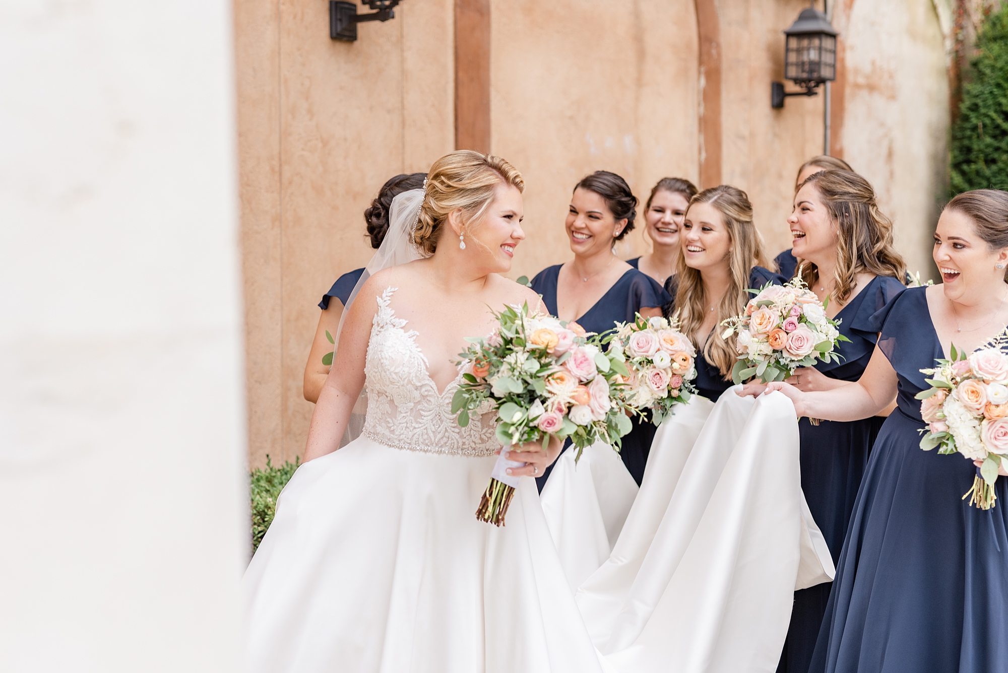 bride walks with bridesmaids holding dress