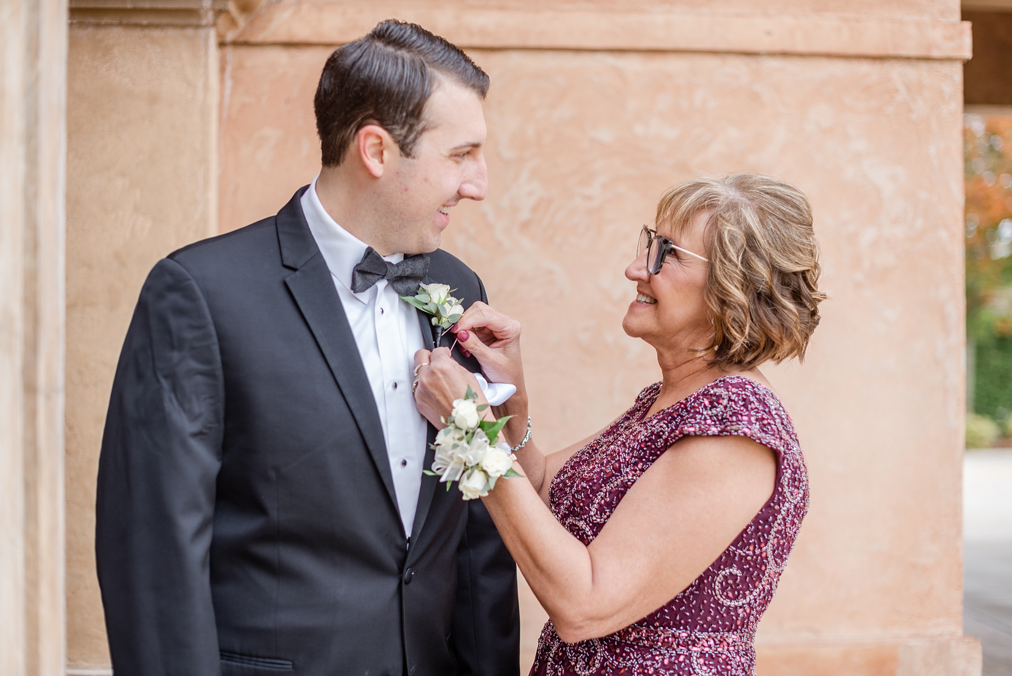 mother of the groom puts boutonnière on