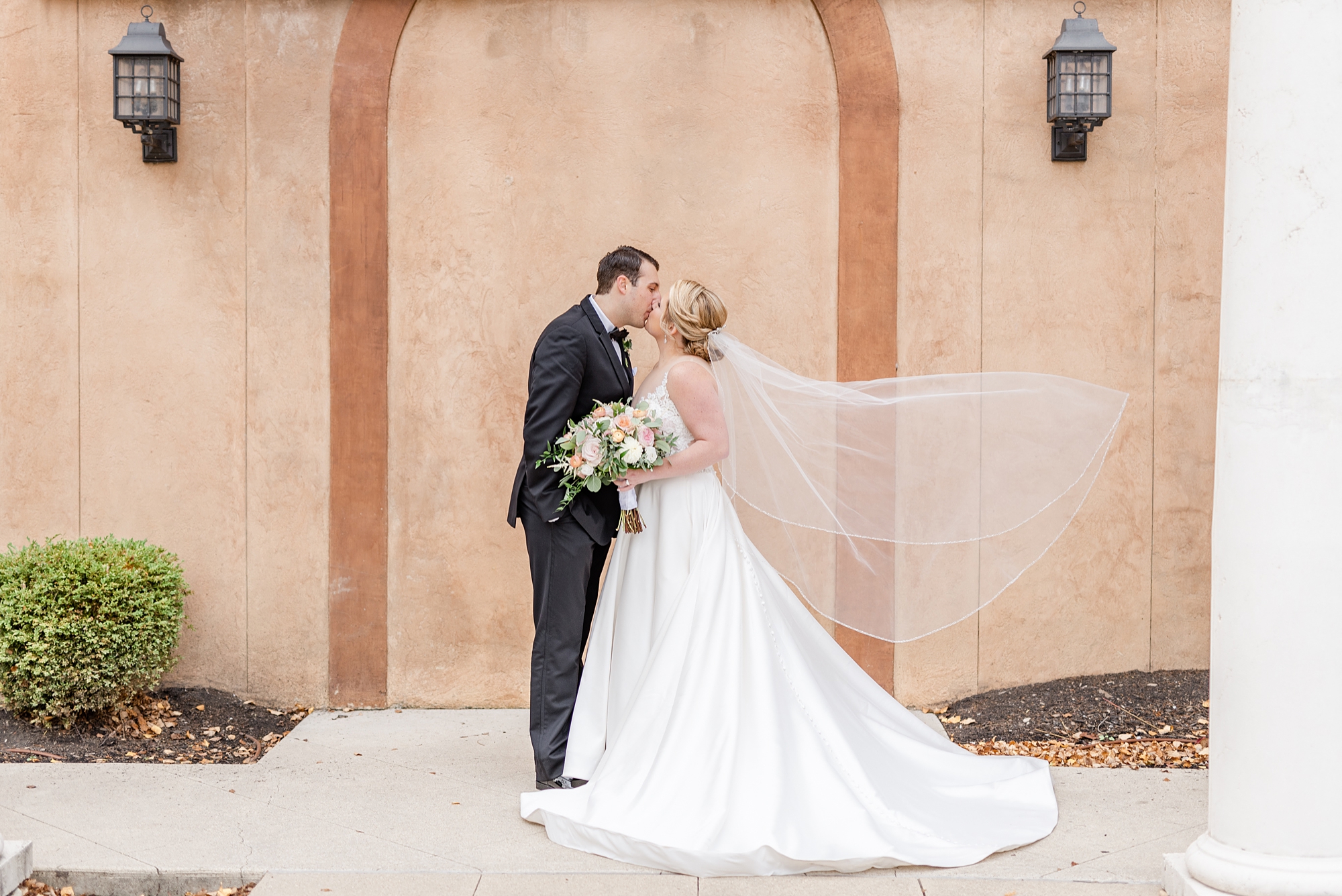 newlyweds kiss outside The Club at Corazon while bride's veil floats