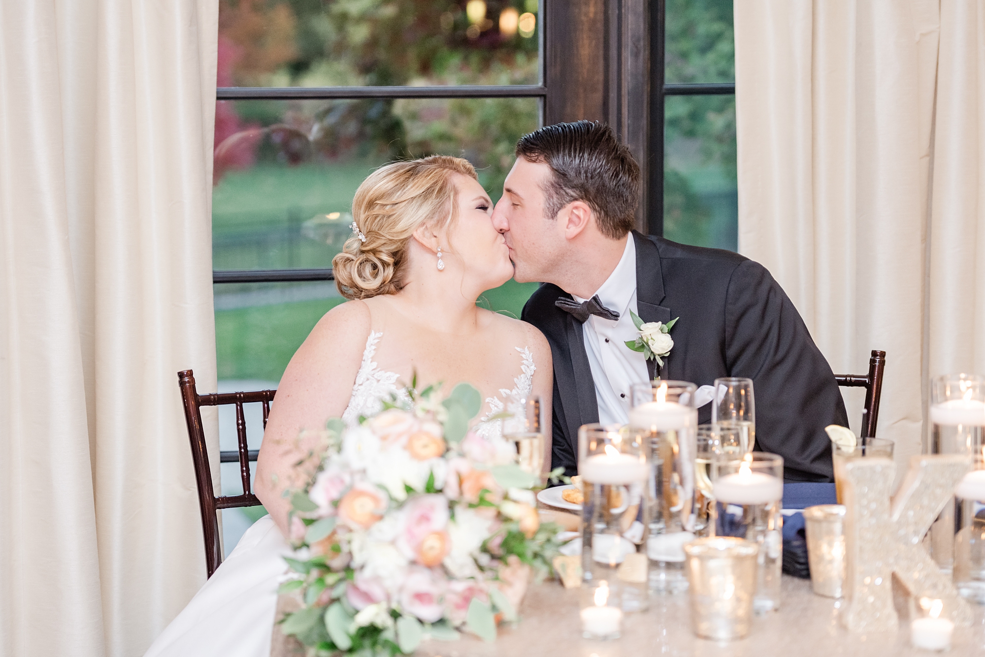 newlyweds kiss at sweetheart table at The Club at Corazon wedding reception