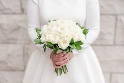 bride holds all white bouquet of roses