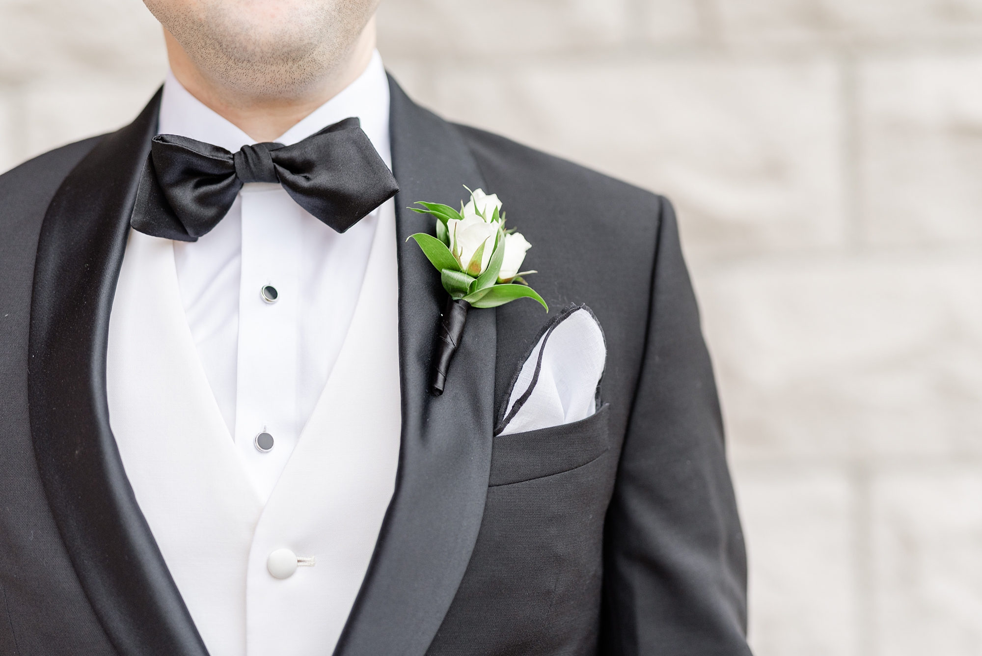 groom in black suit with white boutonnière