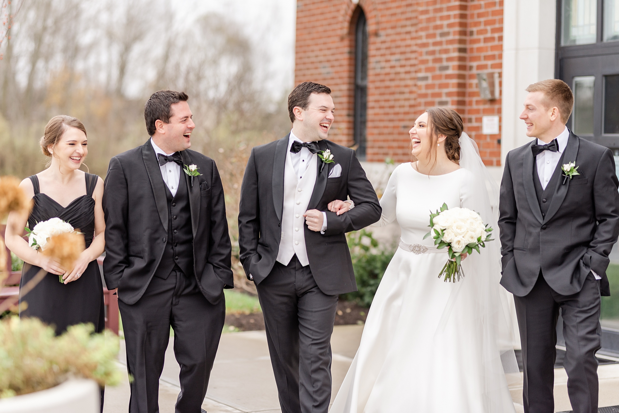 bride laughs while walking with bridesmaids and groomsmen
