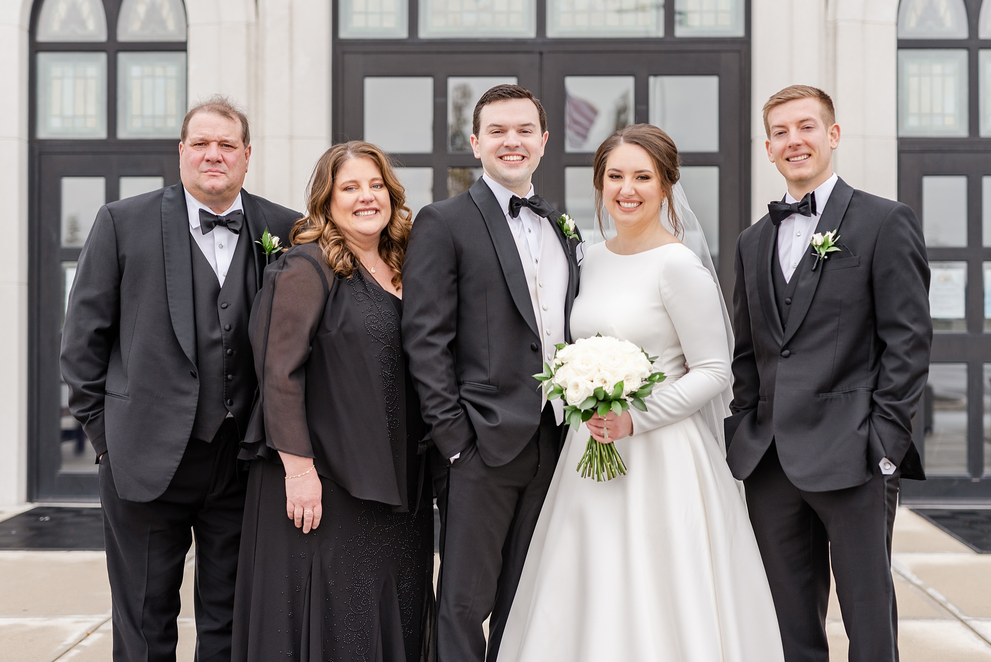 bride and groom pose with family outside church