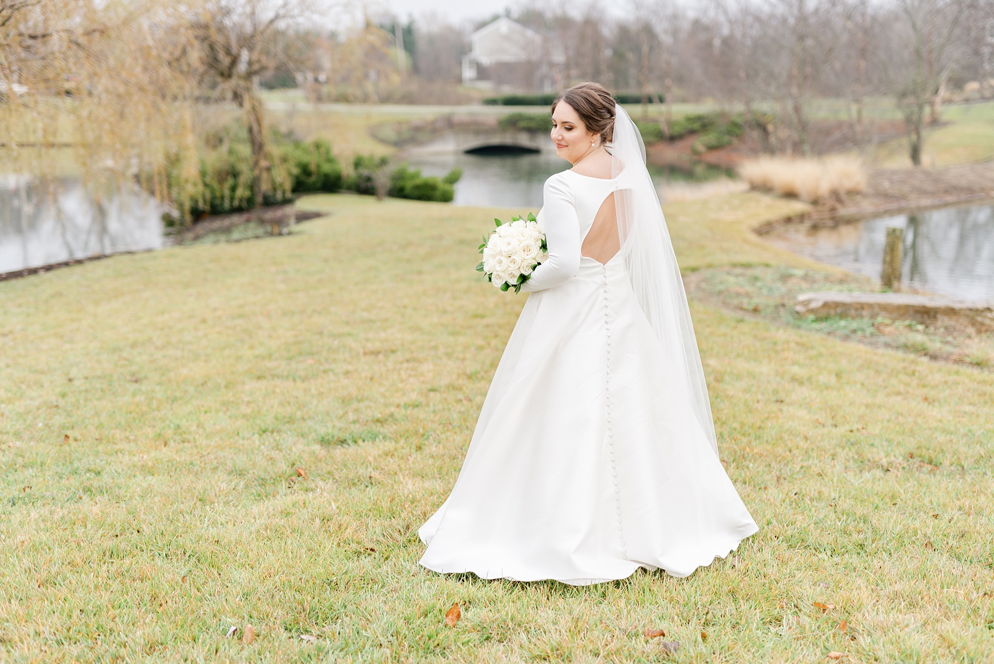 bride shows off back of classic wedding gown