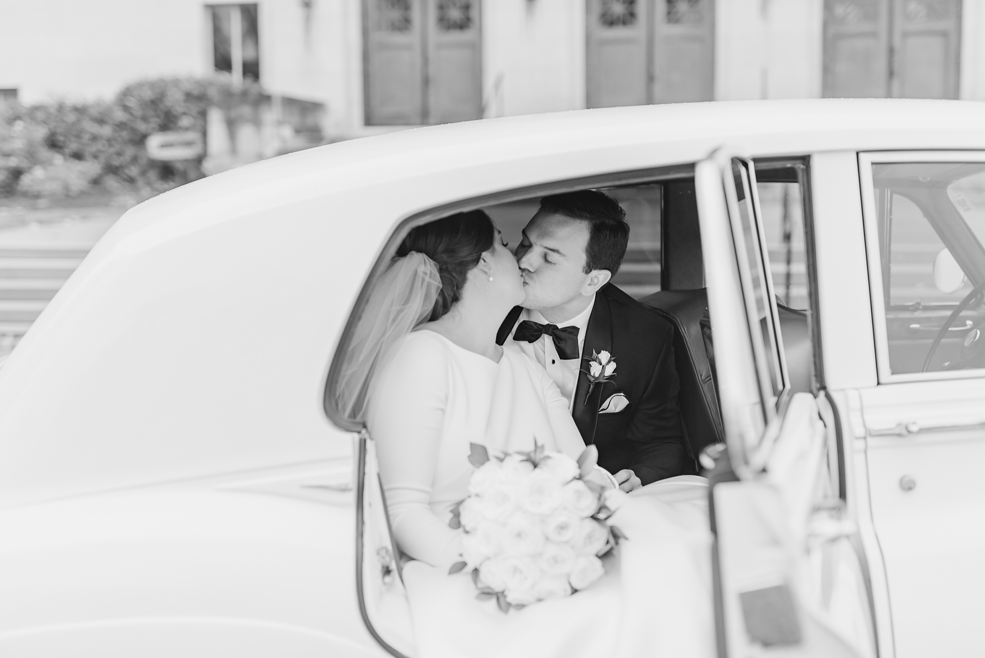 bride and groom kiss in Rolls Royce