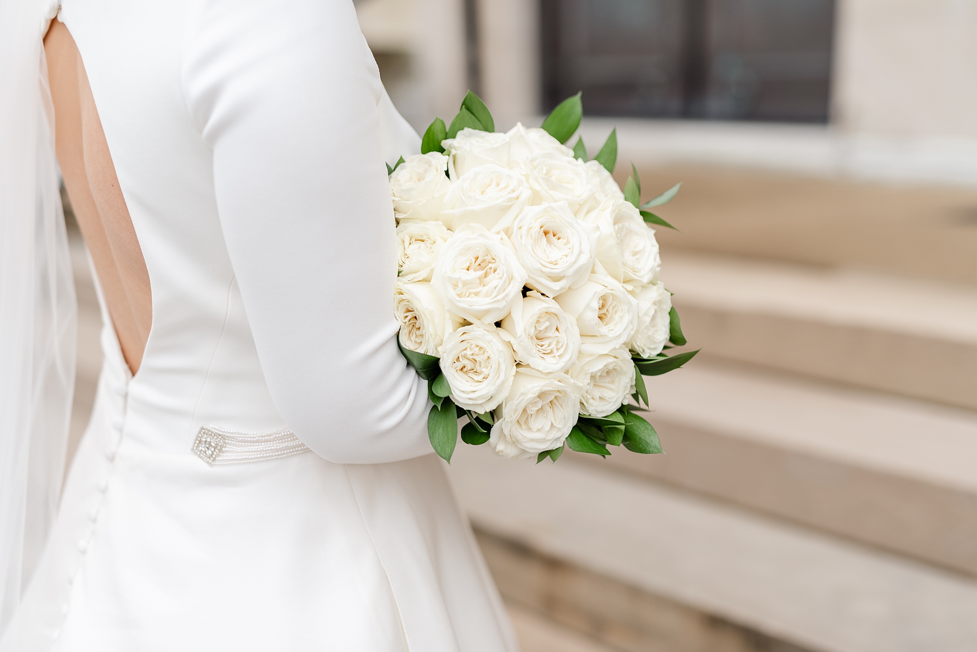 bride holds bouquet of ivory roses