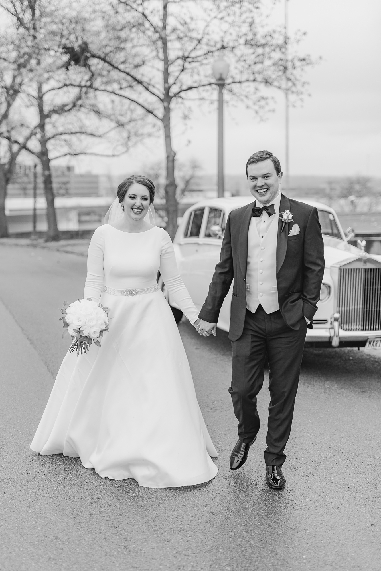 bride and groom walk in front of Rolls Royce
