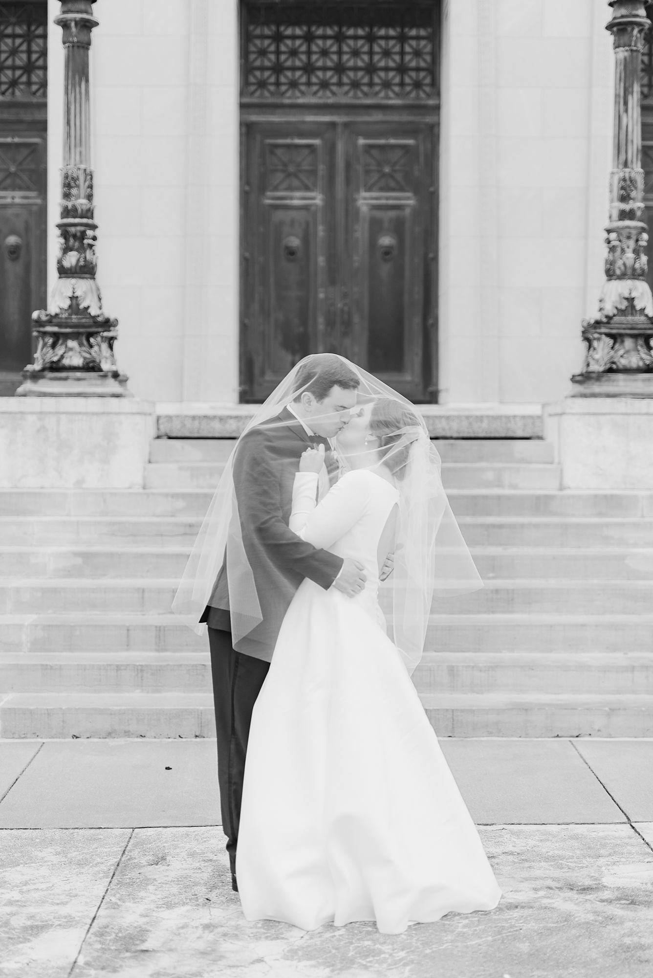 bride and groom kiss under veil in front of Dayton Masonic Center